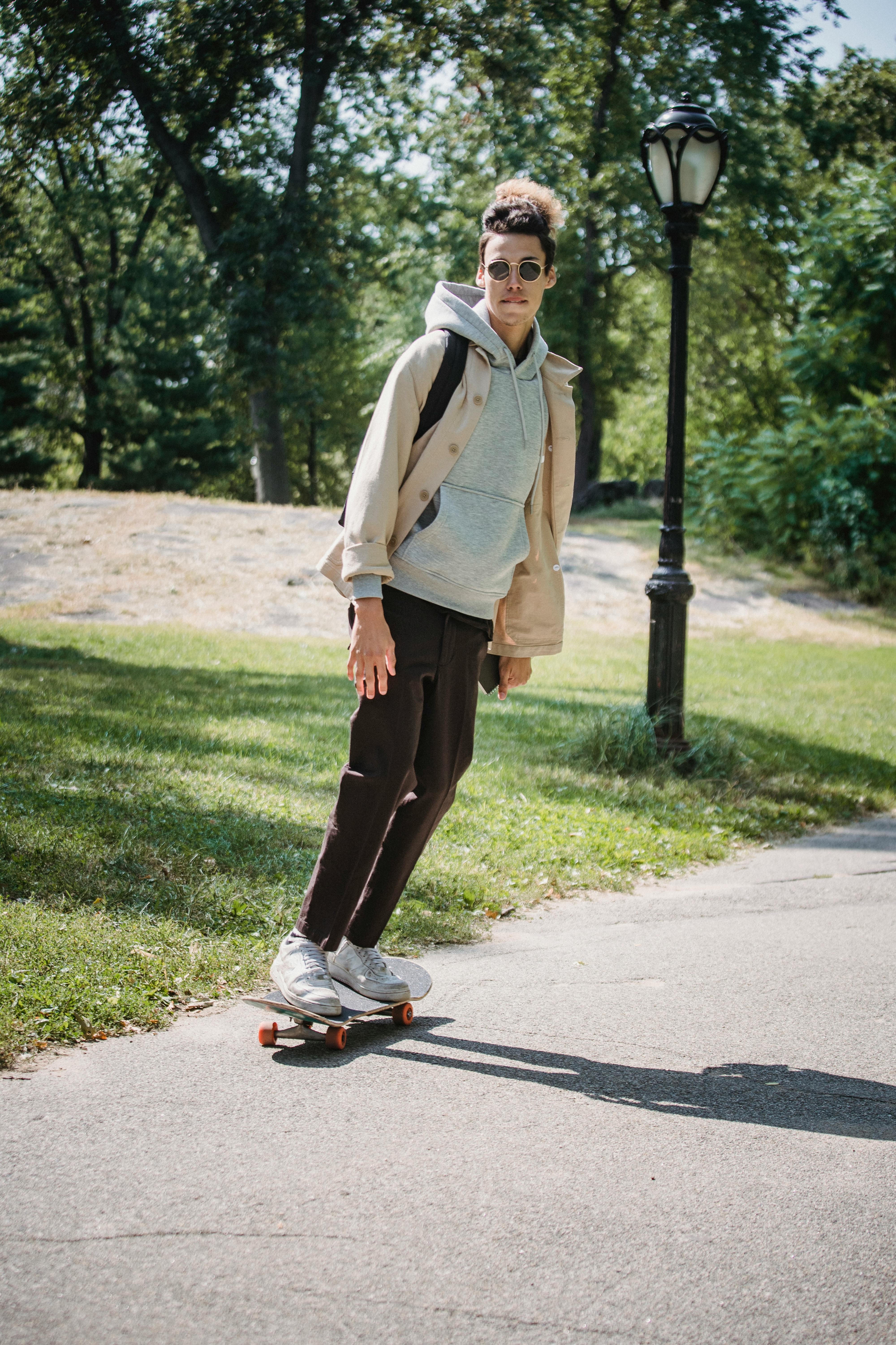 stylish man riding skateboard in park
