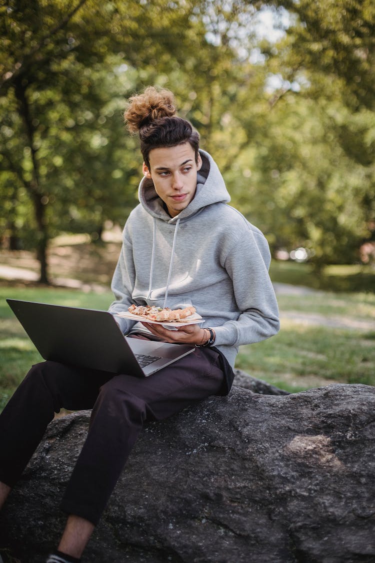 Serious Student Using Laptop And Eating Pizza