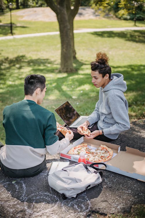 Male students having pizza during break in studies