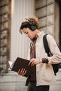 一名戴着耳机的年轻人在一栋石头建筑外的文件夹里学习