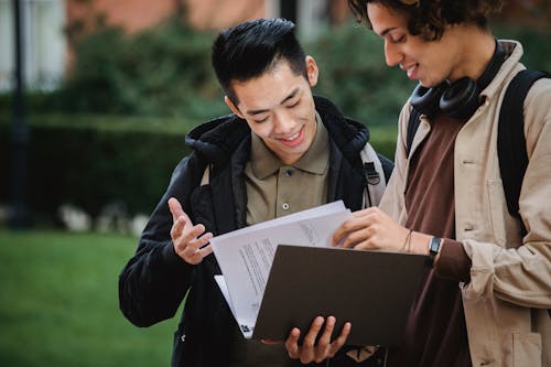 Multiethnic students reading report in folder together