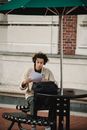 Concentrated male student in casual clothes reading papers with task while sitting at table in campus