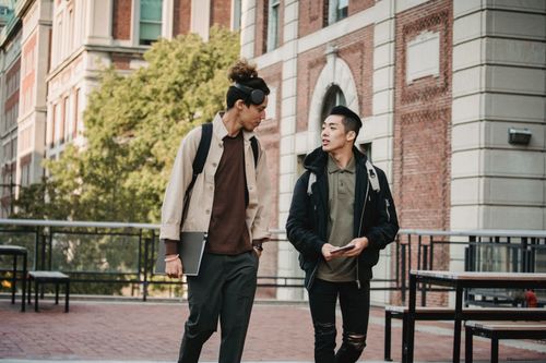 Free Young multiethnic men in casual informal outfit and stylish haircuts promenading and discussing new project while looking at each other Stock Photo