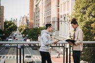 两个年轻人在城市桥梁上，以城市景观为背景，一起学习