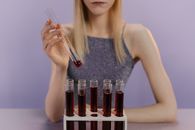 一名妇女在实验室里处理试管中的红色液体，进行科学研究