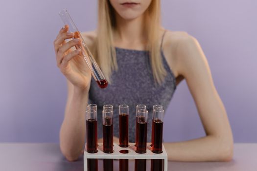 一名妇女在实验室里处理试管中的红色液体，进行科学研究