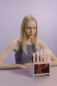 一名金发女子表情怪异，坐在冒着烟的试管前，营造出一种诡异的万圣节氛围