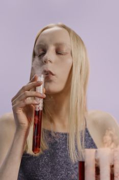 紫色背景下，一位皮肤苍白、金发的年轻女子从试管中喷出烟雾