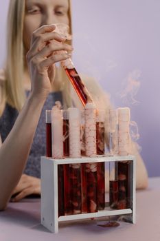 一名妇女手持一根装有红色液体的试管，试管中冒出烟雾，营造出一种幽灵般的氛围