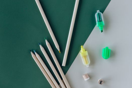 绿色和白色背景上的艺术用品，如铅笔和荧光笔，非常适合创意项目