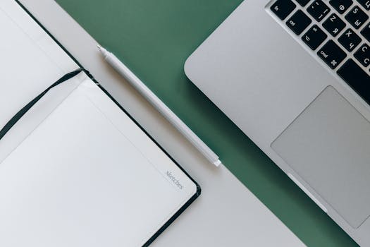 Minimalist workspace with laptop, notepad, and pen for sketching and note-taking.