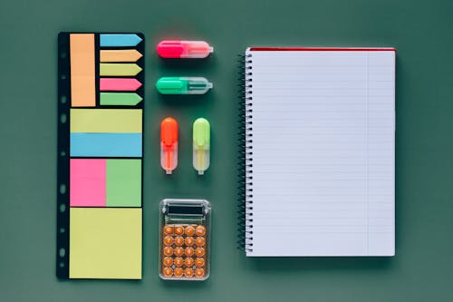 Free Spiral Notebook Beside Markers and a Calculator Stock Photo