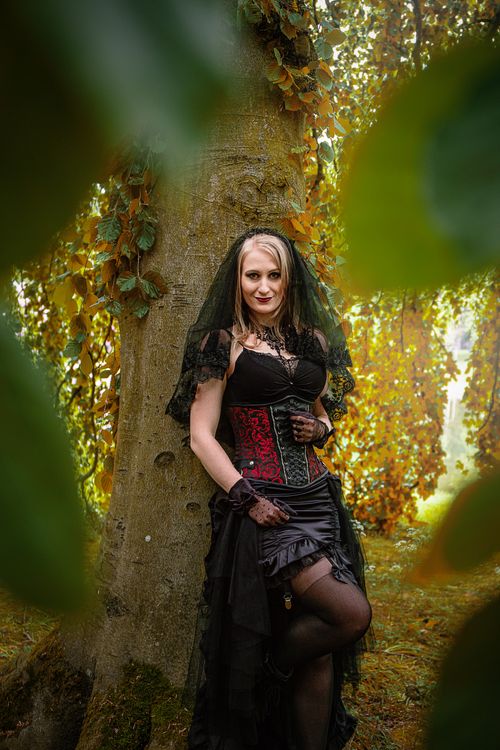 Free Elegant woman in gothic attire posing in an autumn forest setting with vibrant foliage. Stock Photo