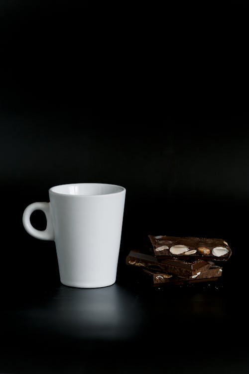 White Ceramic Cup Beside a Chocolate Bar