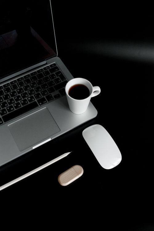 Free Top view of a laptop, coffee cup, and accessories on a black background. Stock Photo