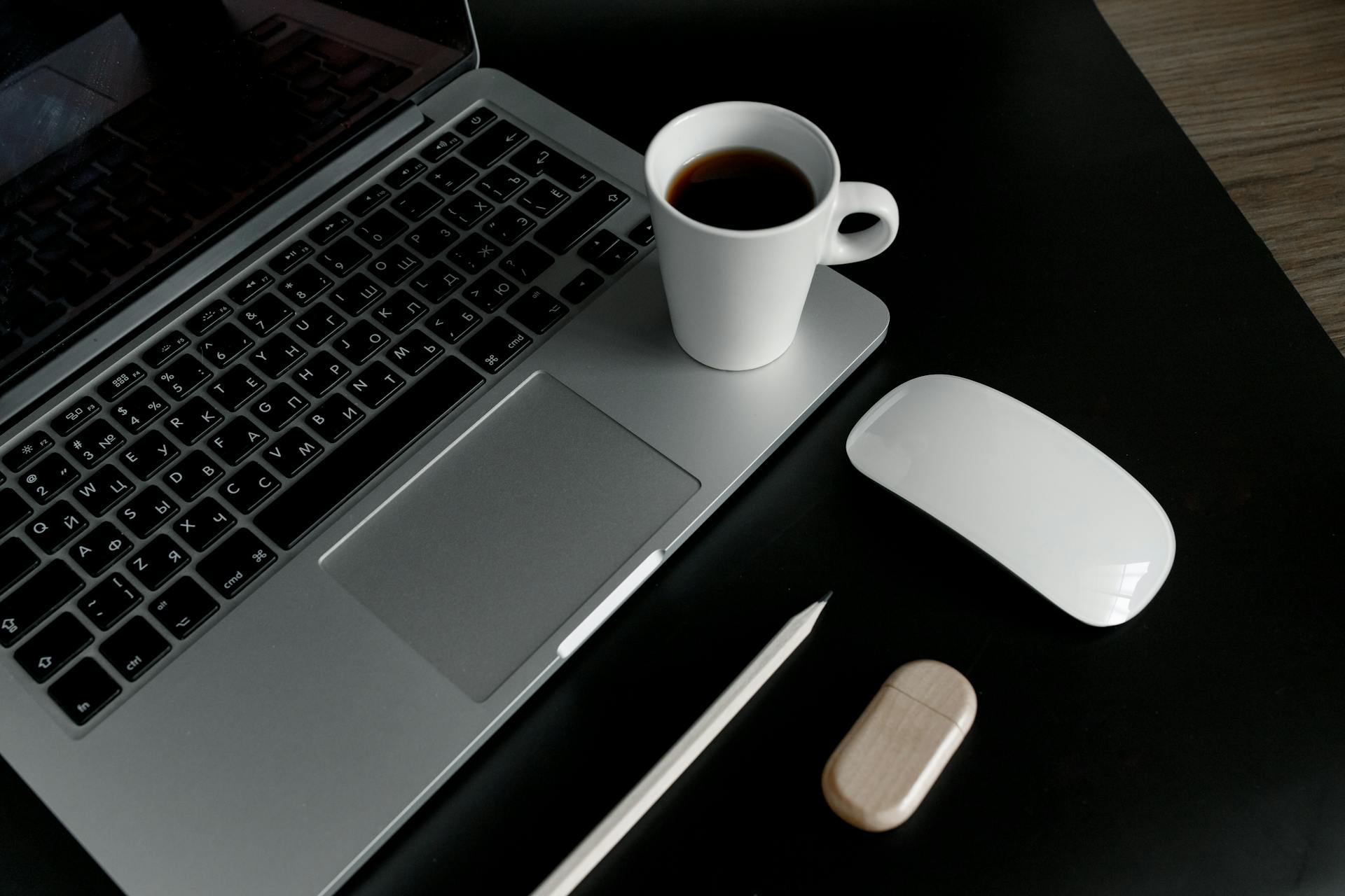 A sleek, minimalist desk setup featuring a laptop, coffee cup, and accessories.