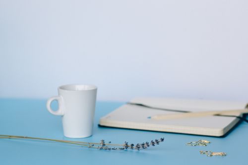 Free A serene minimalist workspace features a ceramic cup, notebook, lavender flower, and office supplies. Stock Photo
