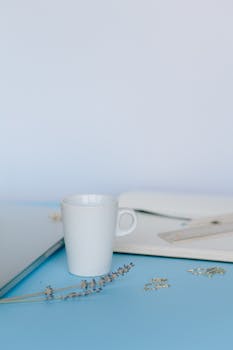 A serene workspace featuring a ceramic cup, lavender, and stationery items on a blue desk.