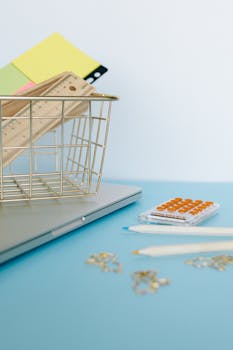 Minimalist office setup with supplies on a blue desk including calculator and laptop.