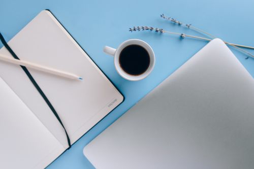 Free Top view of a minimal workspace featuring a notebook, coffee, and lavender on a blue background. Stock Photo