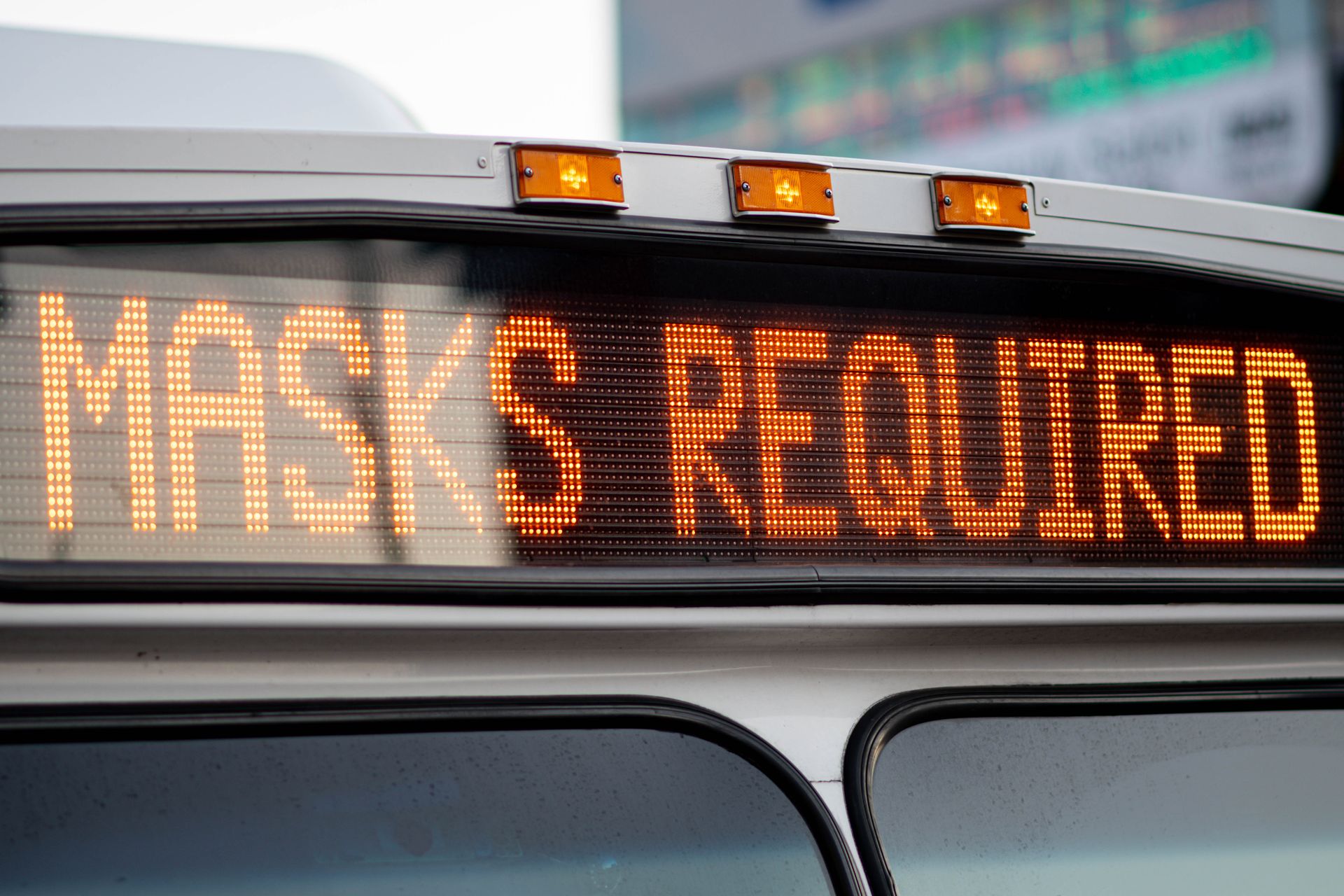 Close-up of a bus display sign showing 'Masks Required' for COVID-19 public transportation safety.