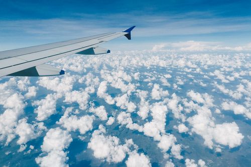 Free Aerial view of modern metal airplane wing in blue sky over fluffy clouds Stock Photo