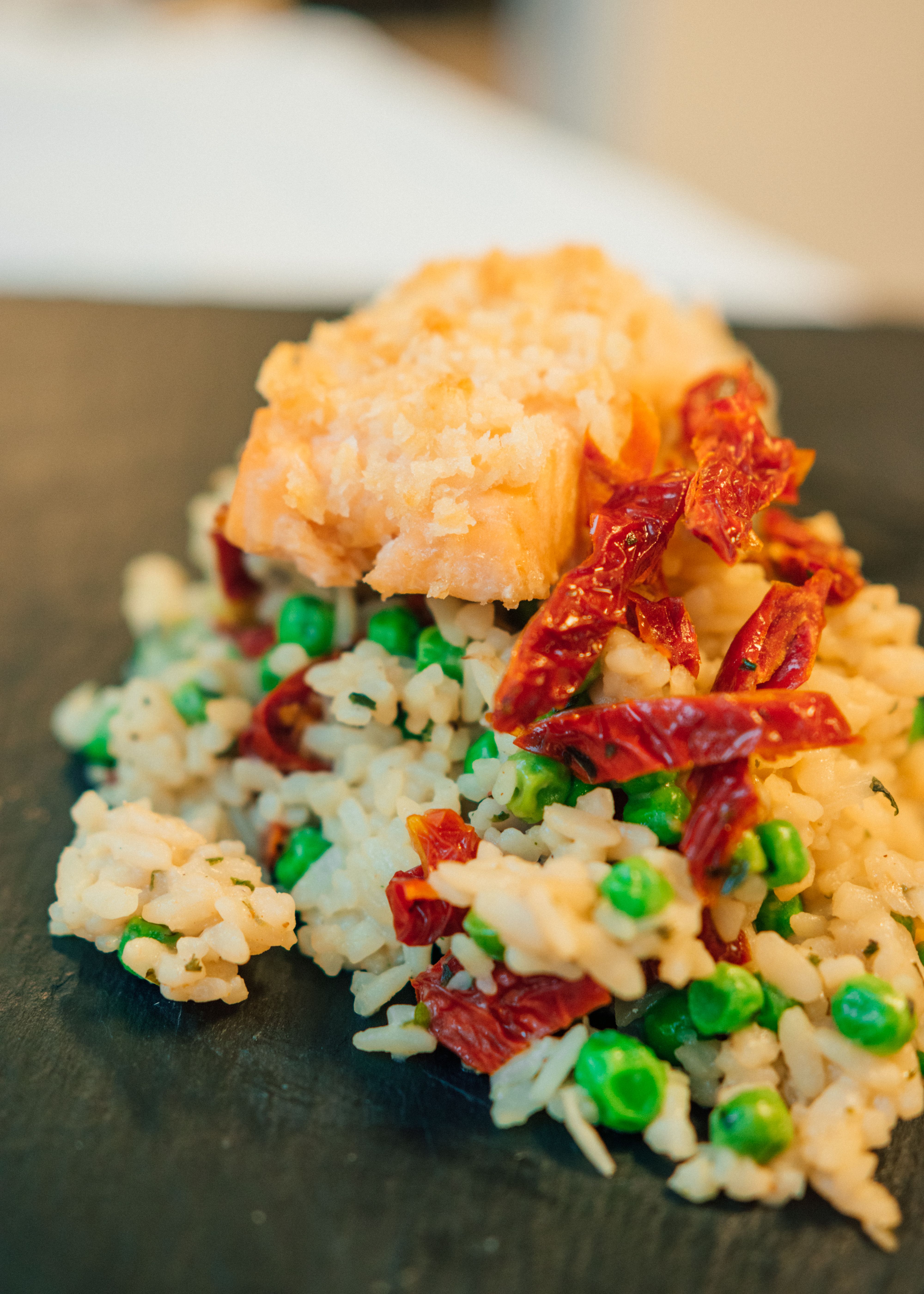 Delicious salmon served on a bed of rice mixed with green peas and sun-dried tomatoes.