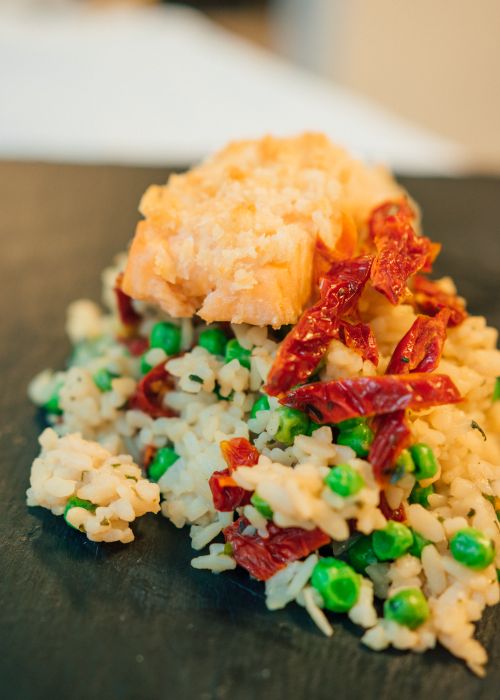 Free Delicious salmon served on a bed of rice mixed with green peas and sun-dried tomatoes. Stock Photo