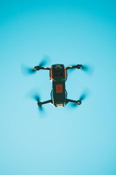Drone captured from below against a vibrant blue sky showing motion blur.