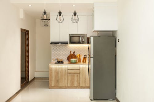 Gray Top Mount Refrigerator Beside Brown Wooden Kitchen Cabinet