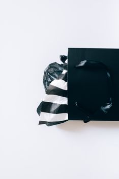 白色背景上，别致的黑色礼品袋装满了时尚的黑白条纹薄纸