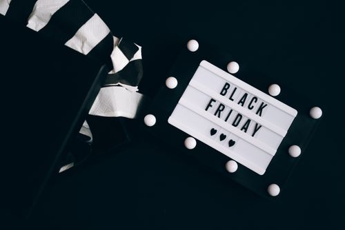 Free A stylish Black Friday sign next to an open gift box with striped tissue paper on a dark background. Stock Photo