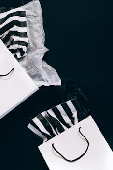 Stylish black and white shopping bags with striped tissue paper, perfect for holiday sales promotions.