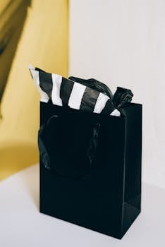 Chic black gift bag with striped tissue paper, ideal for sales and shopping promotions.