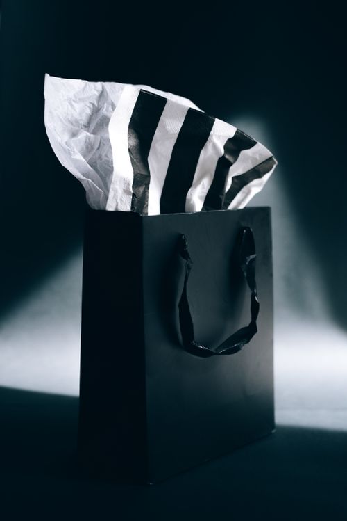 Free Elegant black shopping bag with striped tissue paper, perfect for gift or sale themes. Stock Photo