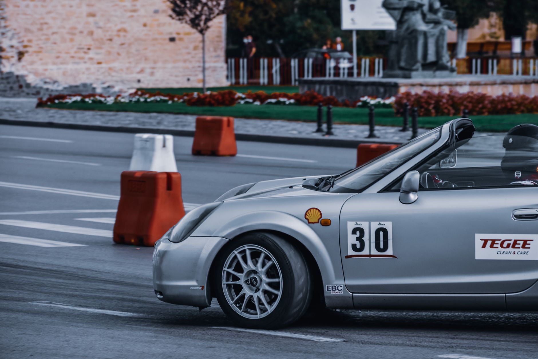 Crop anonymous person in protective helmet driving modern sports car on asphalt road in city in daytime