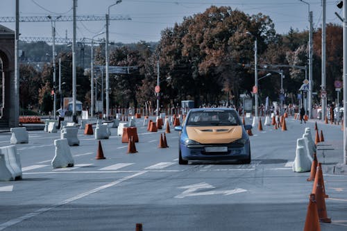 Faceless rider driving classic sport car on asphalt track with traffic cones during race