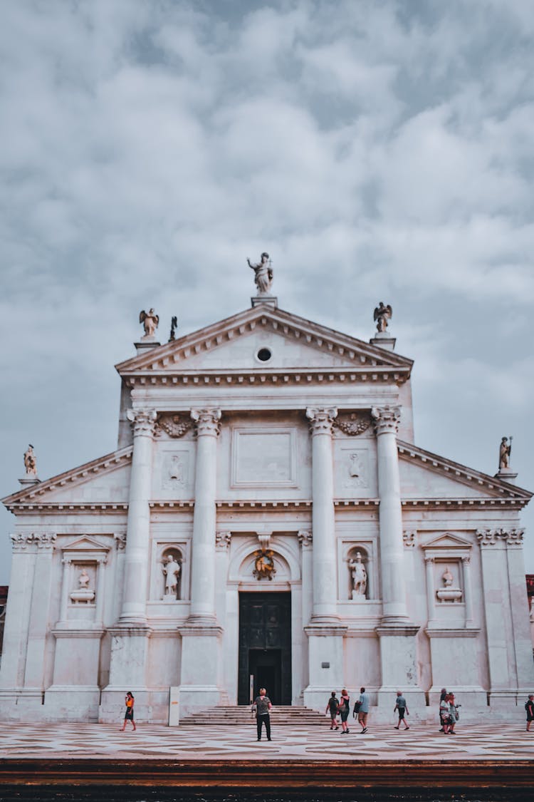 Old Stone Church Exterior With Tourists In Front In Venice Italy