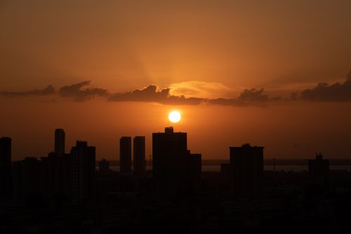 Free Dramatic sunset behind a city skyline with silhouetted buildings, capturing a warm and serene evening. Stock Photo