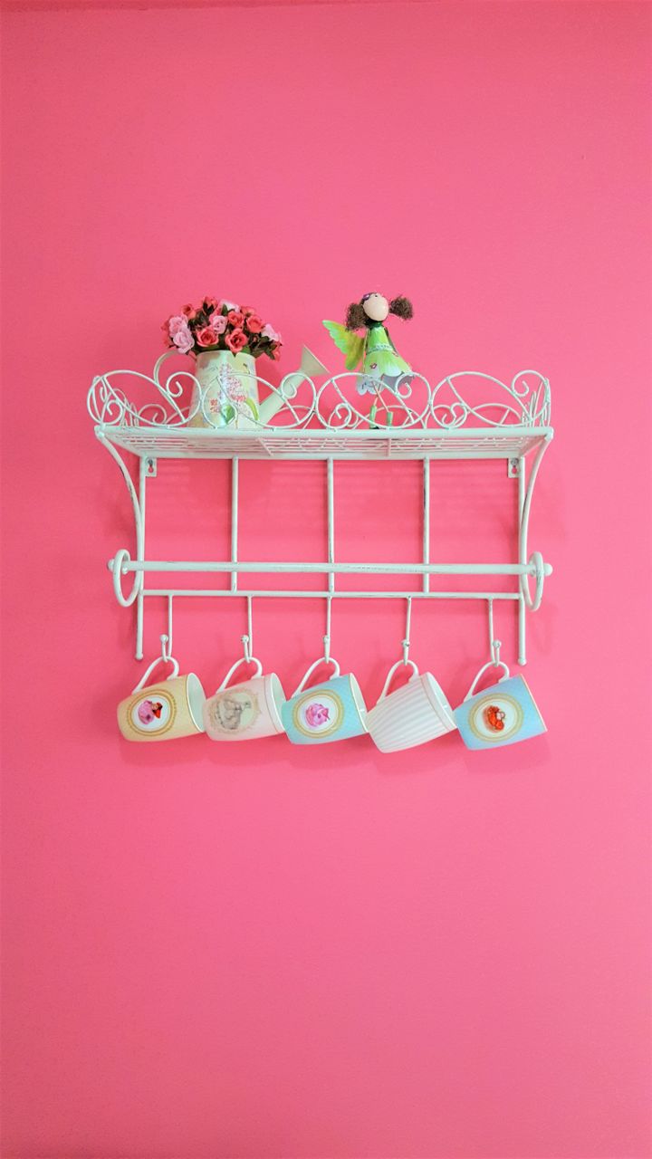 ornate iron vintage mug rack holding colorful ceramic coffee mugs