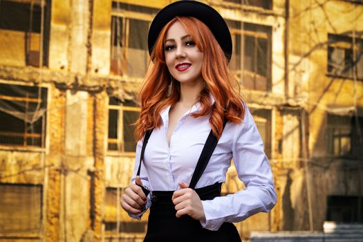 Red-haired woman in vintage attire smiling brightly with a city building background.