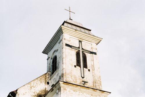 Free Aged white church tower featuring a prominent cross, set against a clear sky. Stock Photo
