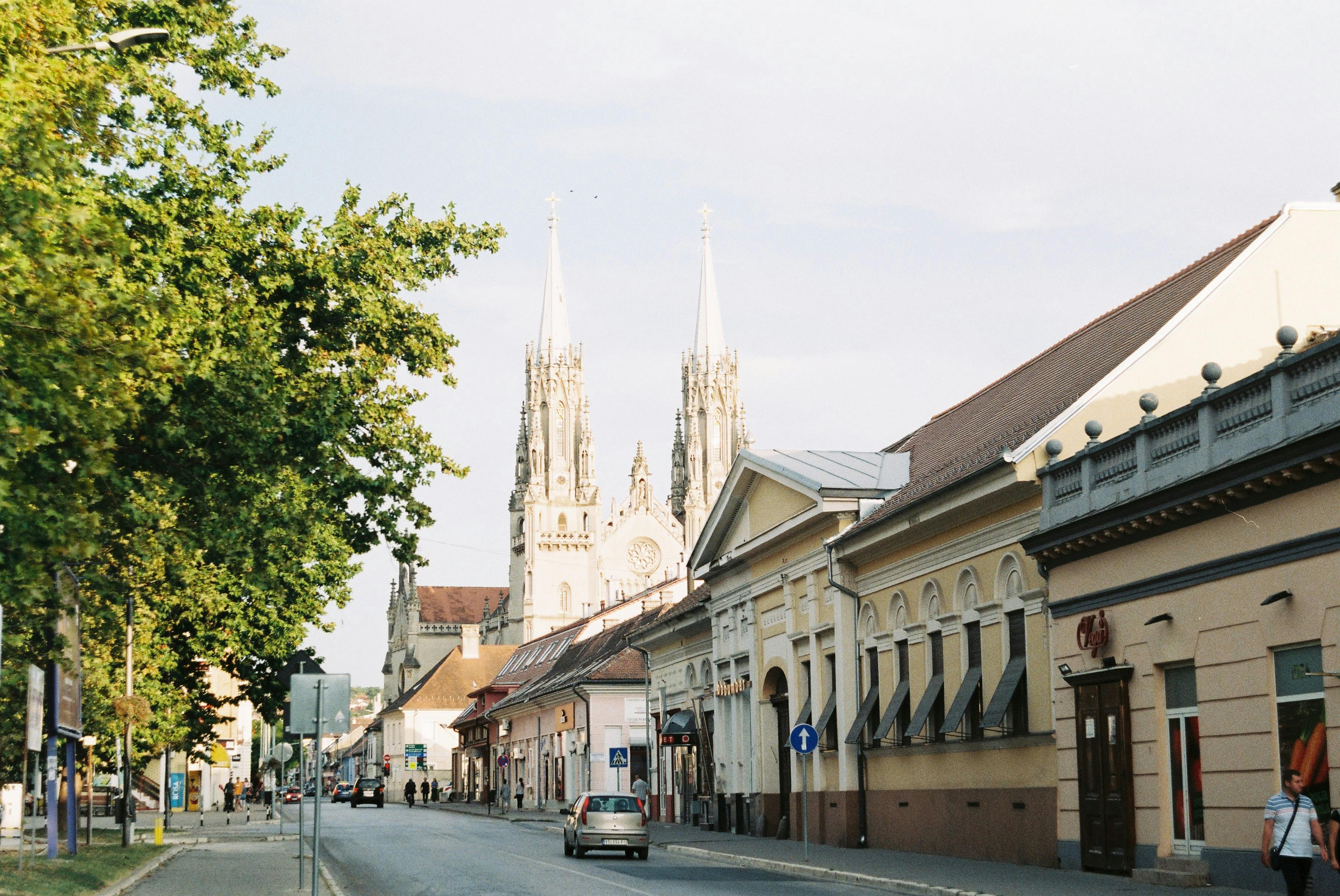 Free A picturesque European street with a historic cathedral in the background, bathed in sunlight. Stock Photo