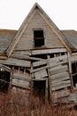 Weathered lumber shed with broken walls and rusty roof located in grassy countryside