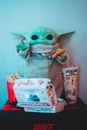 Plastic toy anime figure with chicken cutlet near fast food box and French fries at home