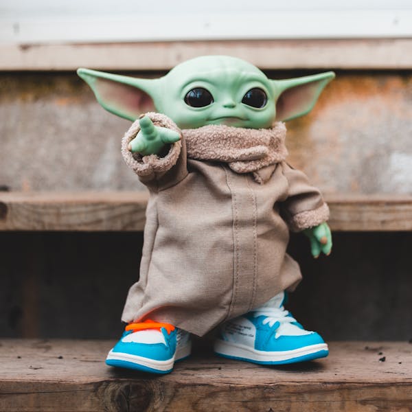 Stylish alien toy figure with trendy sneakers on wooden steps