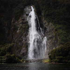 Tall waterfall dropping down a forested granite cliff. Photo by Lawson Davey on Pexels