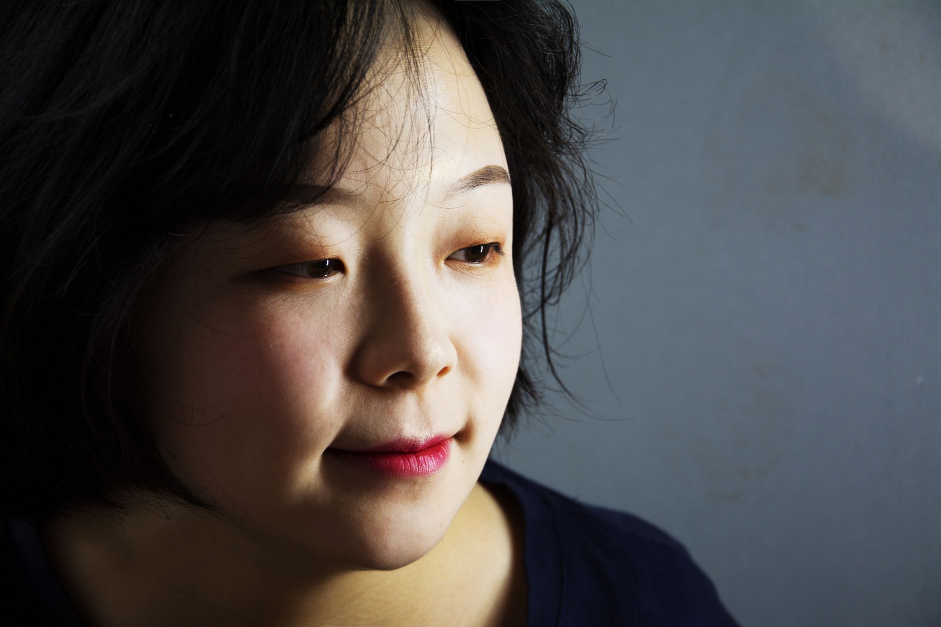 Close-up portrait of a woman with black hair reflecting. Studio setting with soft lighting, capturing a thoughtful expression.