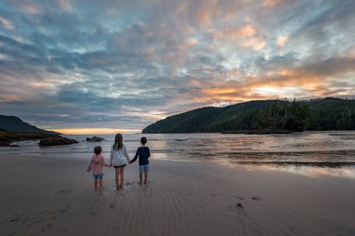 Back View of Children Standing on a Sandy Beach and Cloudscape