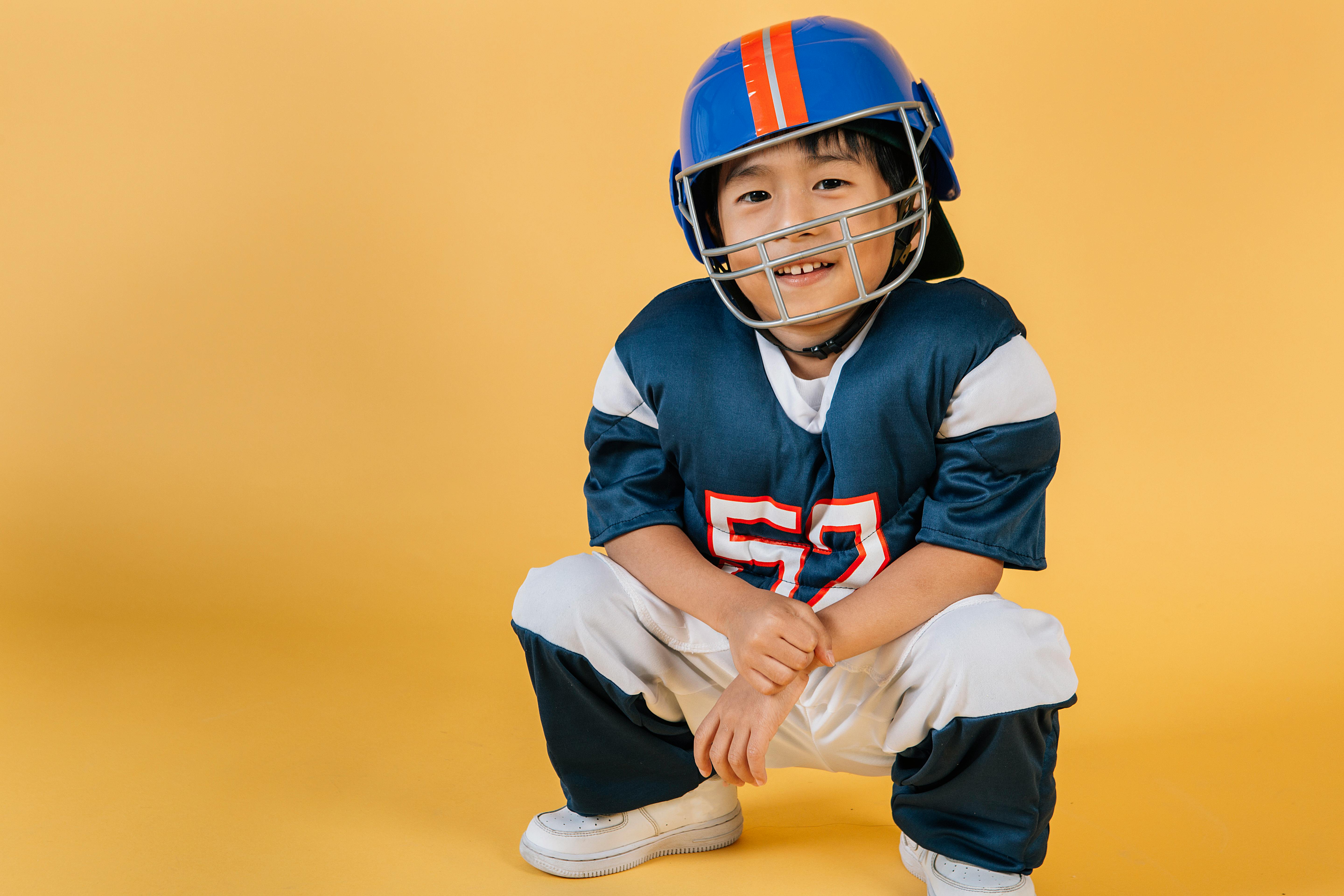 smiling ethnic boy in helmet and uniform of football player